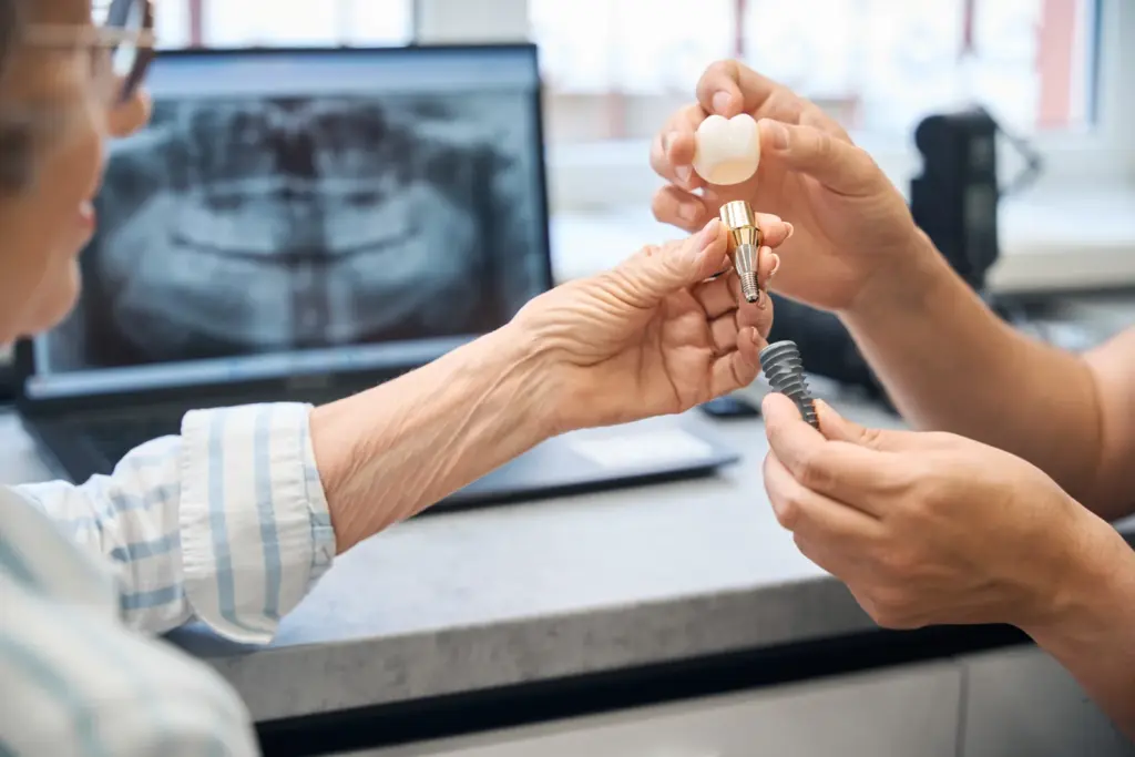 A dentist explaining a dental implant model to an older patient