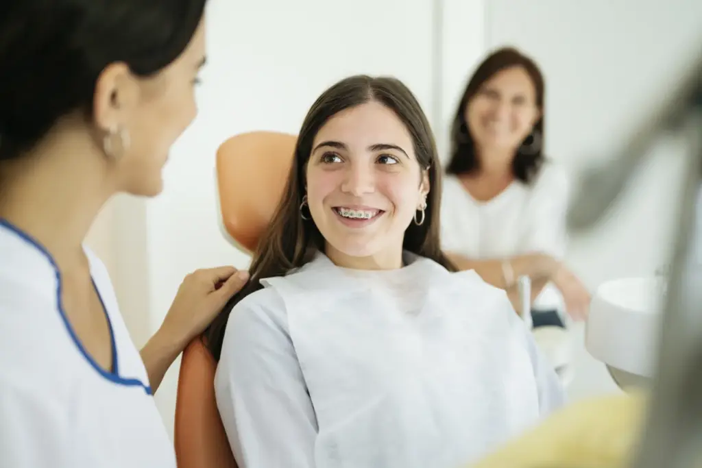 A smiling teenage patient with her dentist