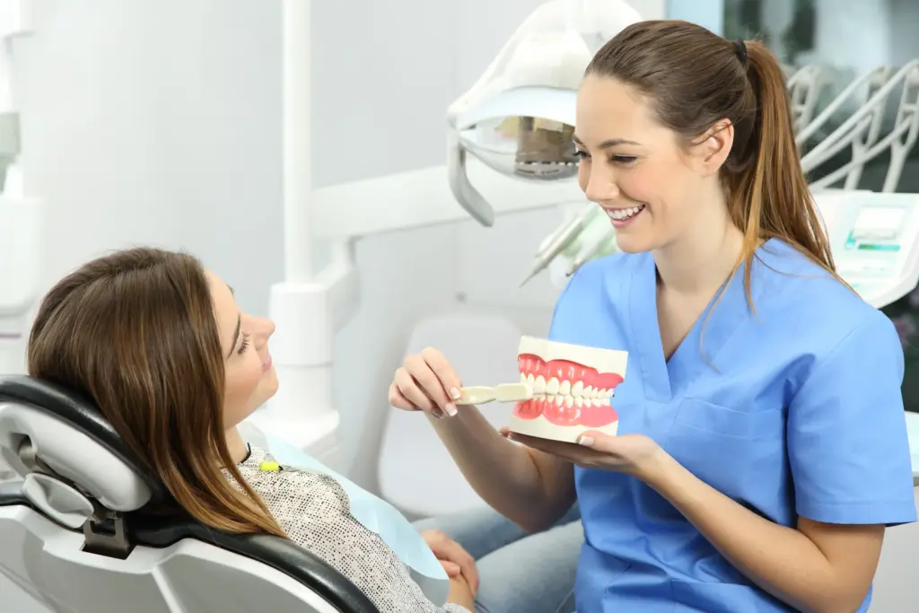 A dentist showing a patient how to brush their teeth during a checkup